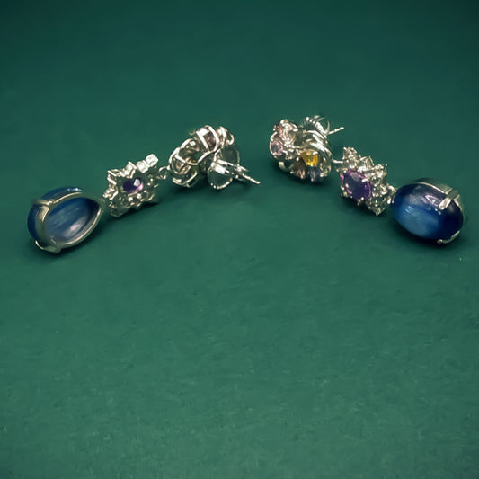 Pair of silver earrings with gemstones on a green background