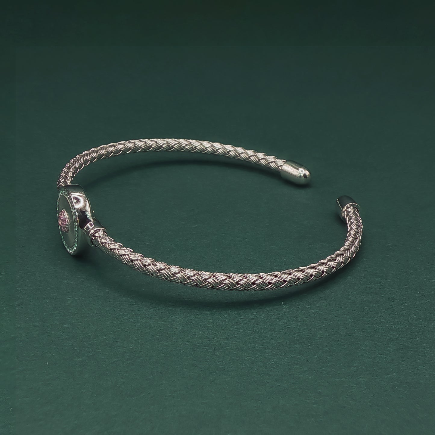 Silver braided bracelet on a dark green background

