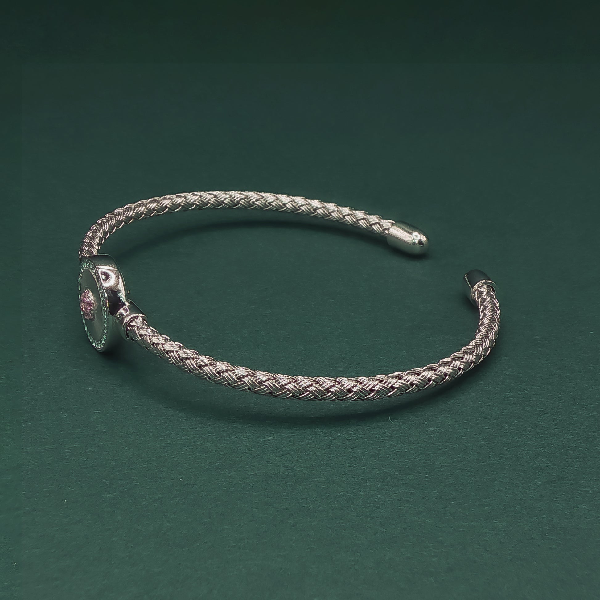 Silver braided bracelet on a dark green background

