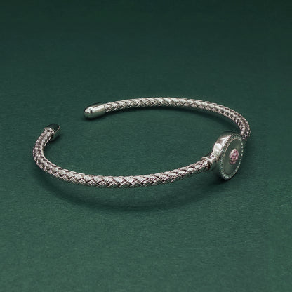 Silver braided bracelet on a dark green background

