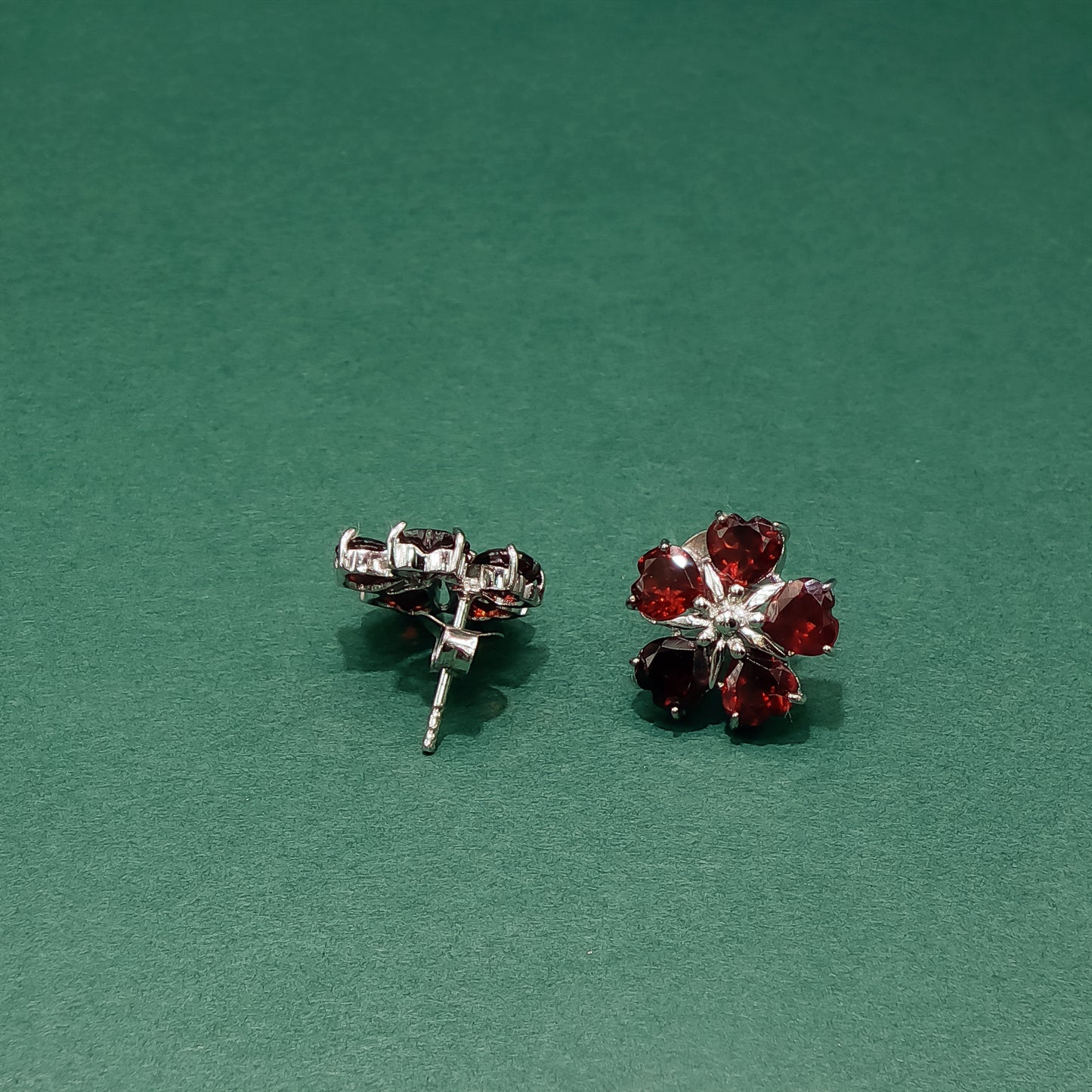 Pair of red gemstone earrings on a green background