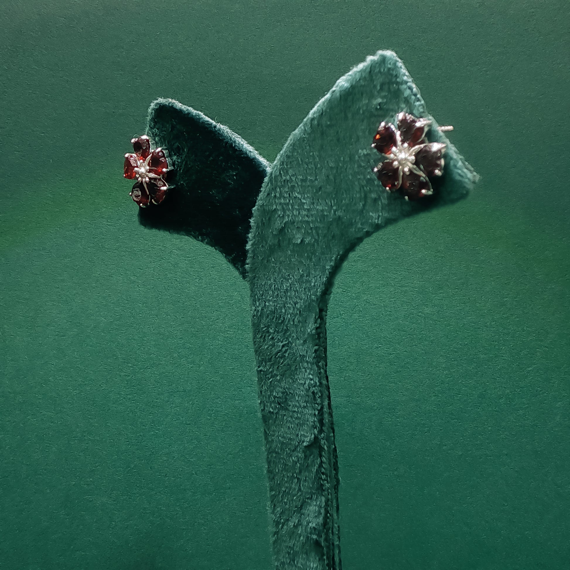 Pair of earrings on a green headband against a green background
