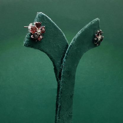 Pair of earrings on a green velvet stand against a green background
