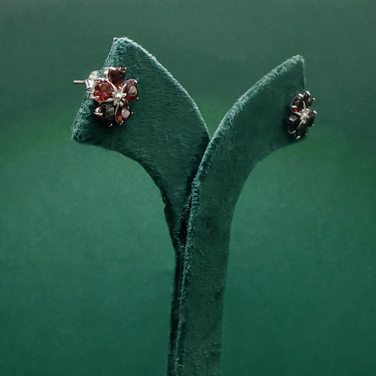 Pair of earrings on a green velvet stand against a green background