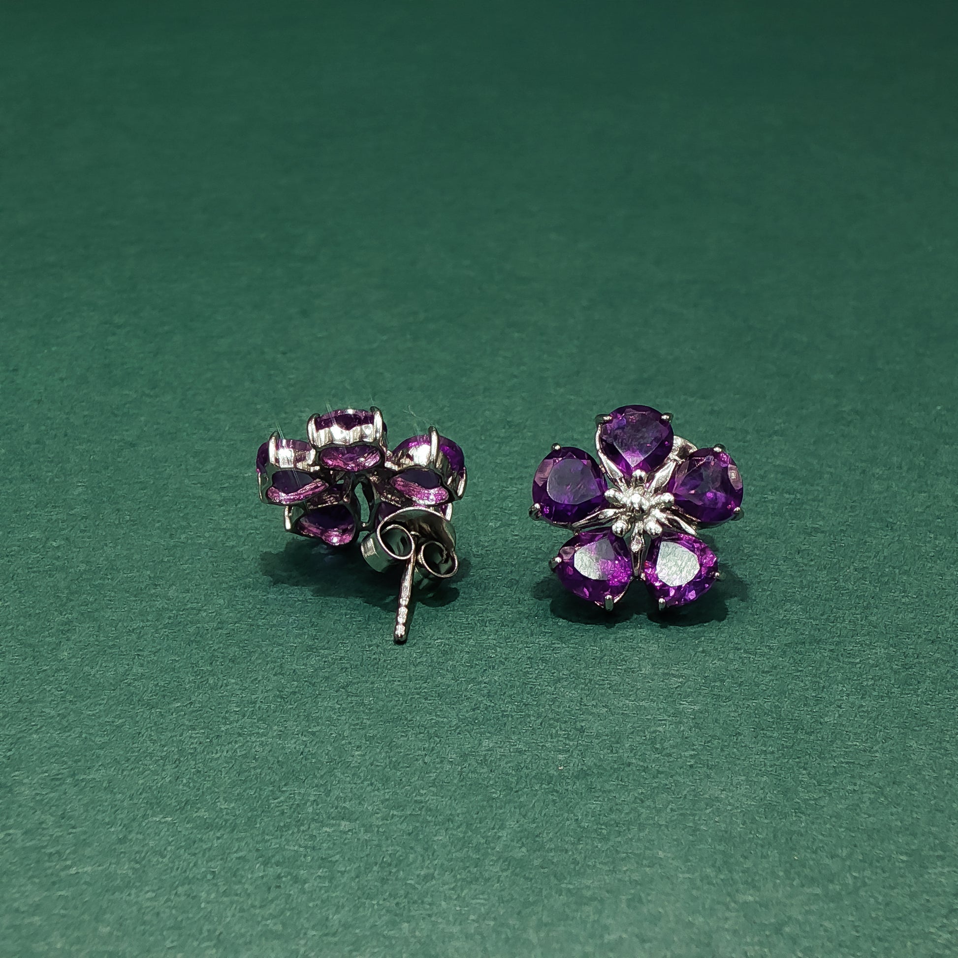 Purple flower-shaped earrings on a green background