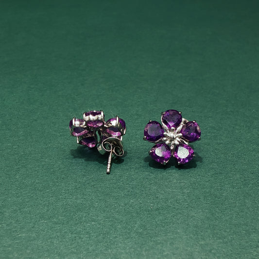 Purple flower-shaped earrings on a green background