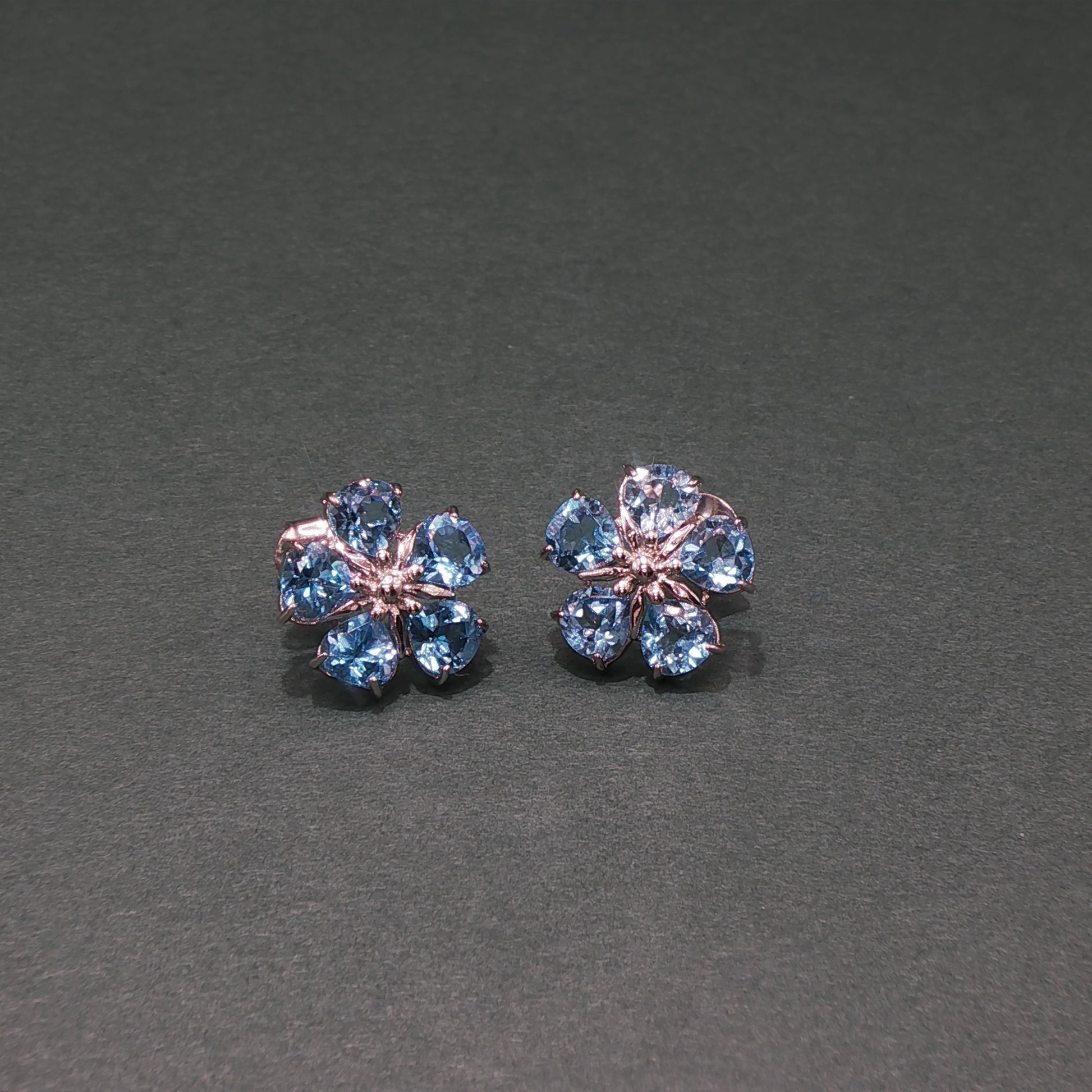 Pair of flower-shaped earrings with blue gemstones on a gray background