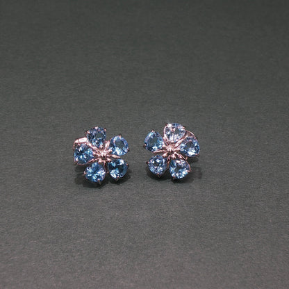 Pair of flower-shaped earrings with blue gemstones on a gray background