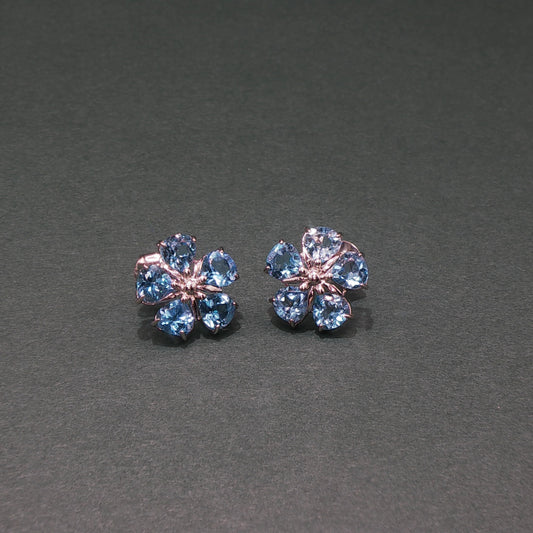 Pair of flower-shaped earrings with blue gemstones on a gray background