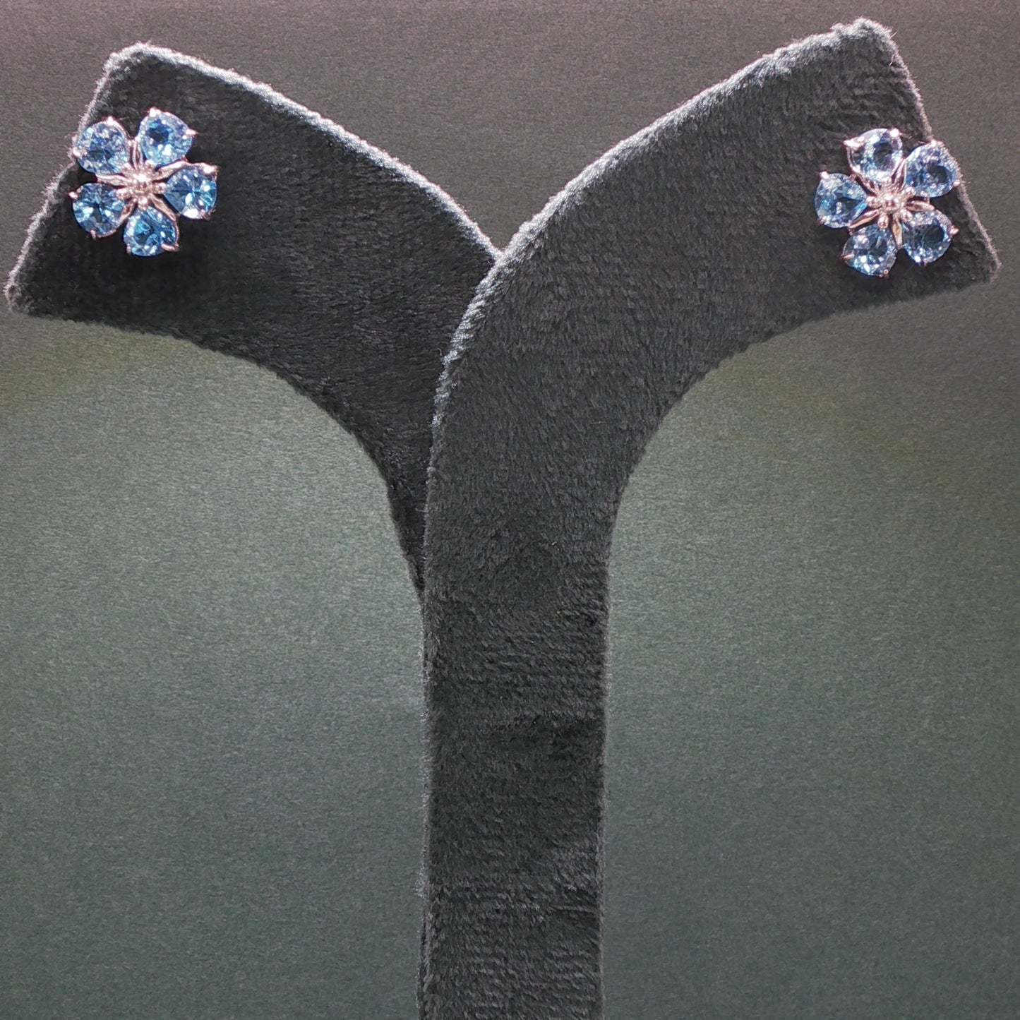 Pair of earrings with blue gemstones on a gray stand