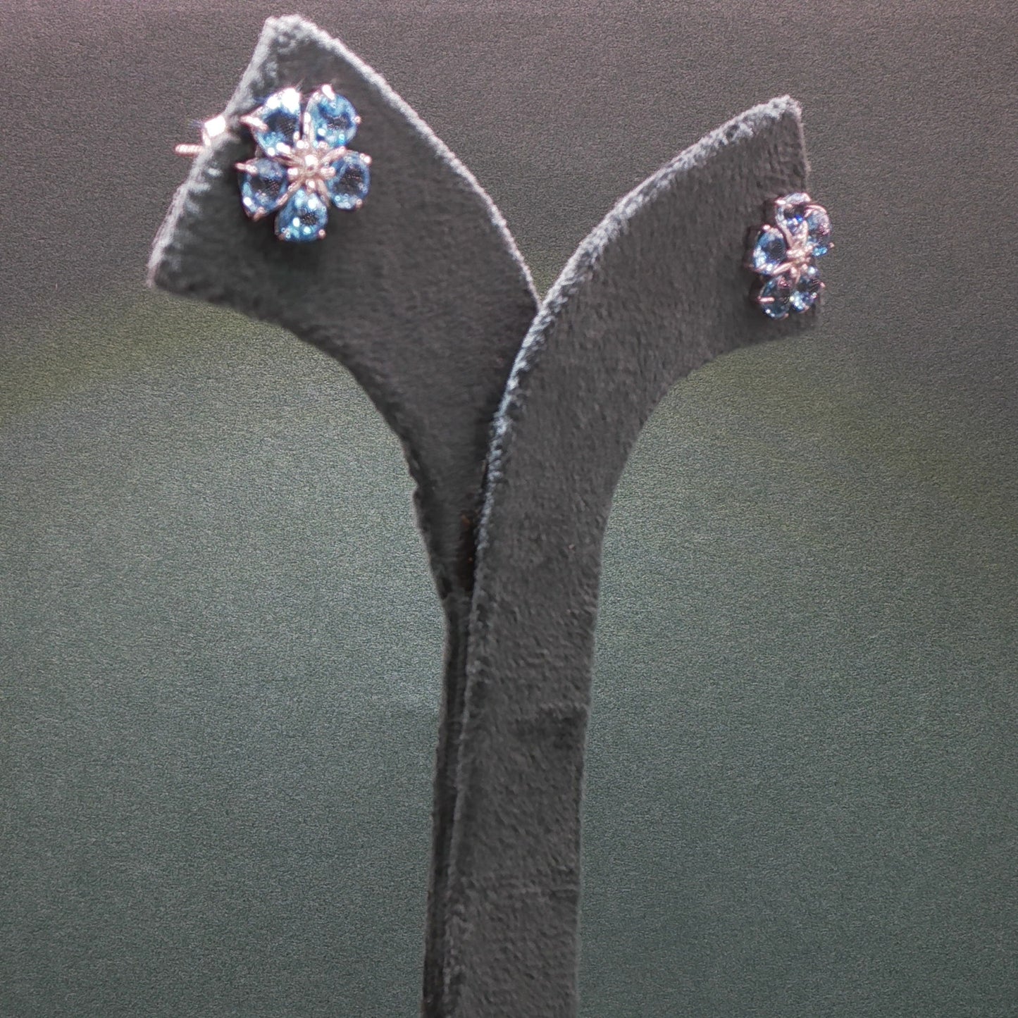 Pair of earrings on a grey stand against a dark background