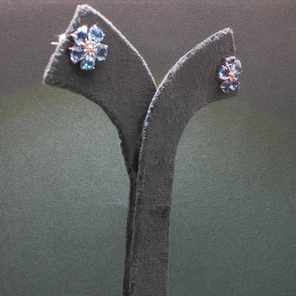 Pair of earrings on a grey stand against a dark background