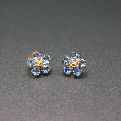 Pair of flower-shaped earrings with blue gemstones on a gray background