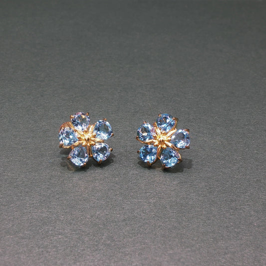 Pair of flower-shaped earrings with blue gemstones on a gray background