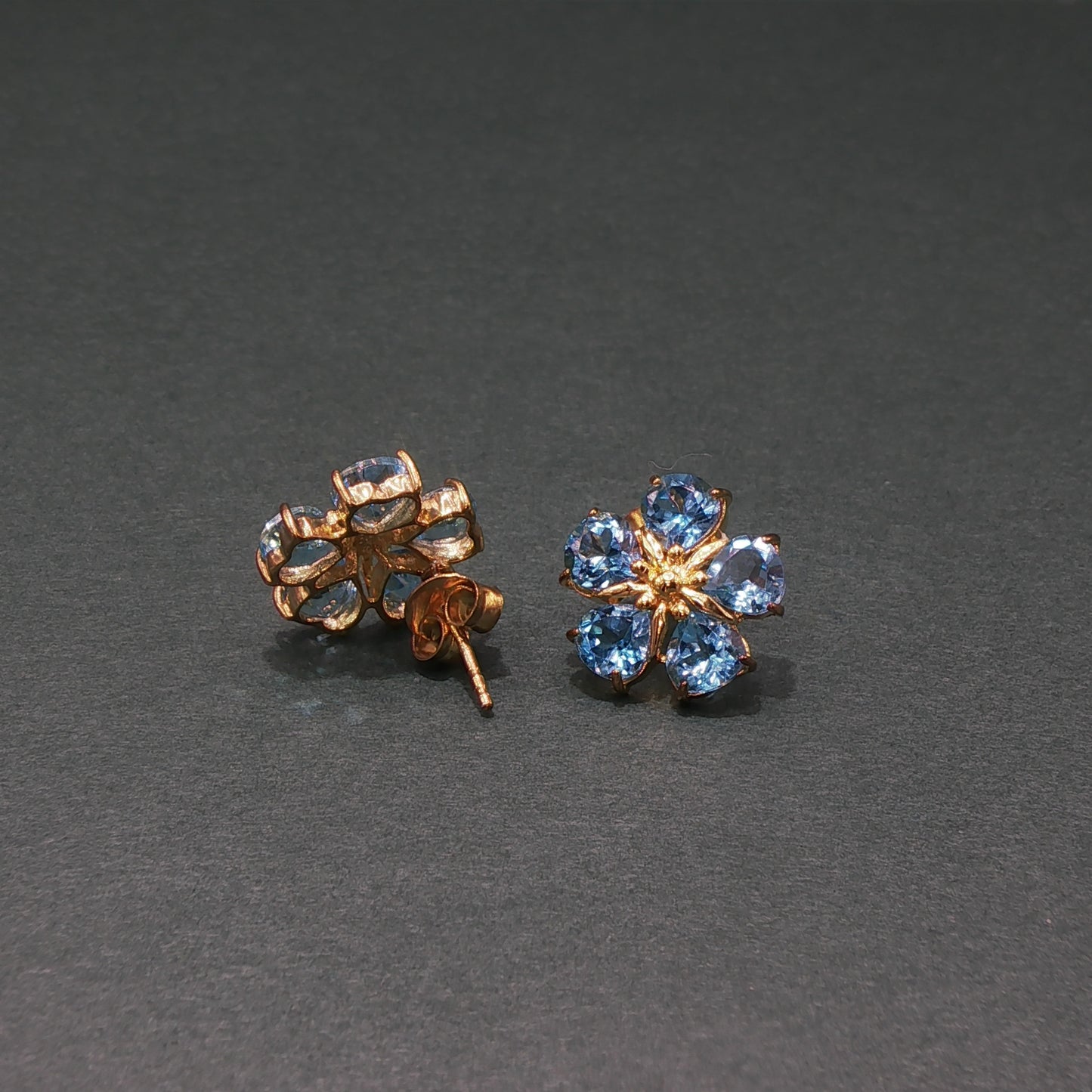 Gold earrings with blue gemstones on a gray background