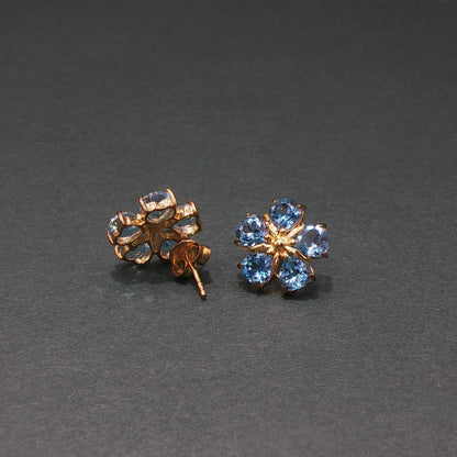 Gold earrings with blue gemstones on a gray background