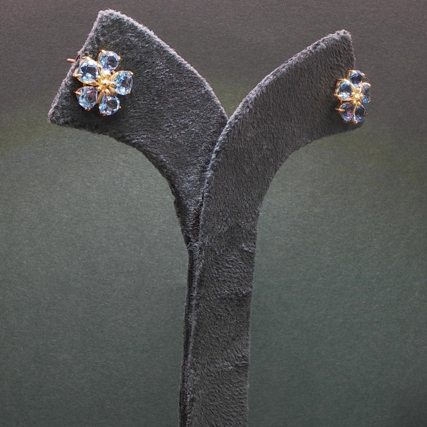 Pair of earrings on a gray stand against a dark background