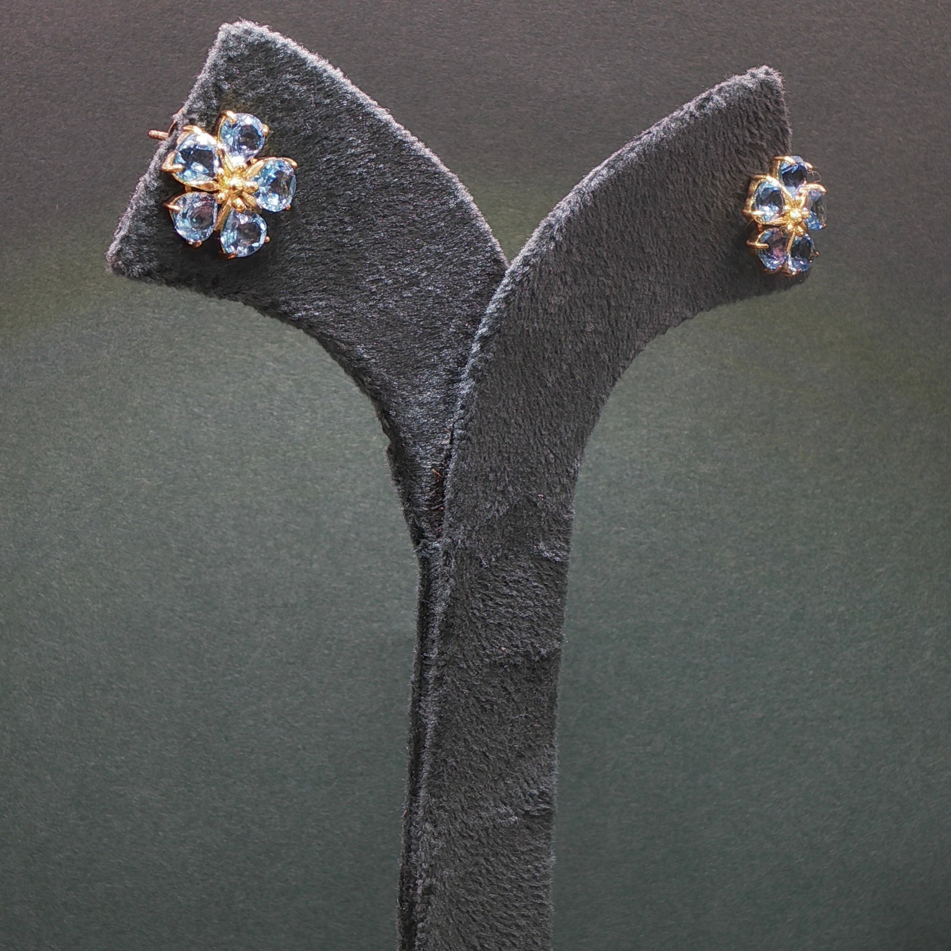 Pair of earrings on a gray stand against a dark background