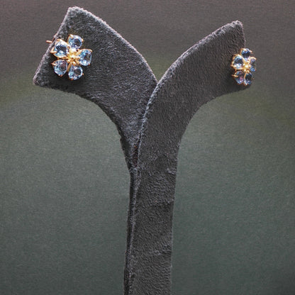 Pair of earrings on a gray stand against a dark background