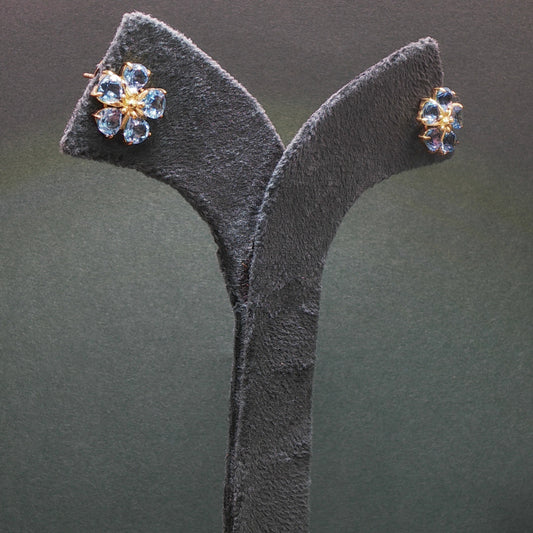 Pair of earrings on a gray stand against a dark background