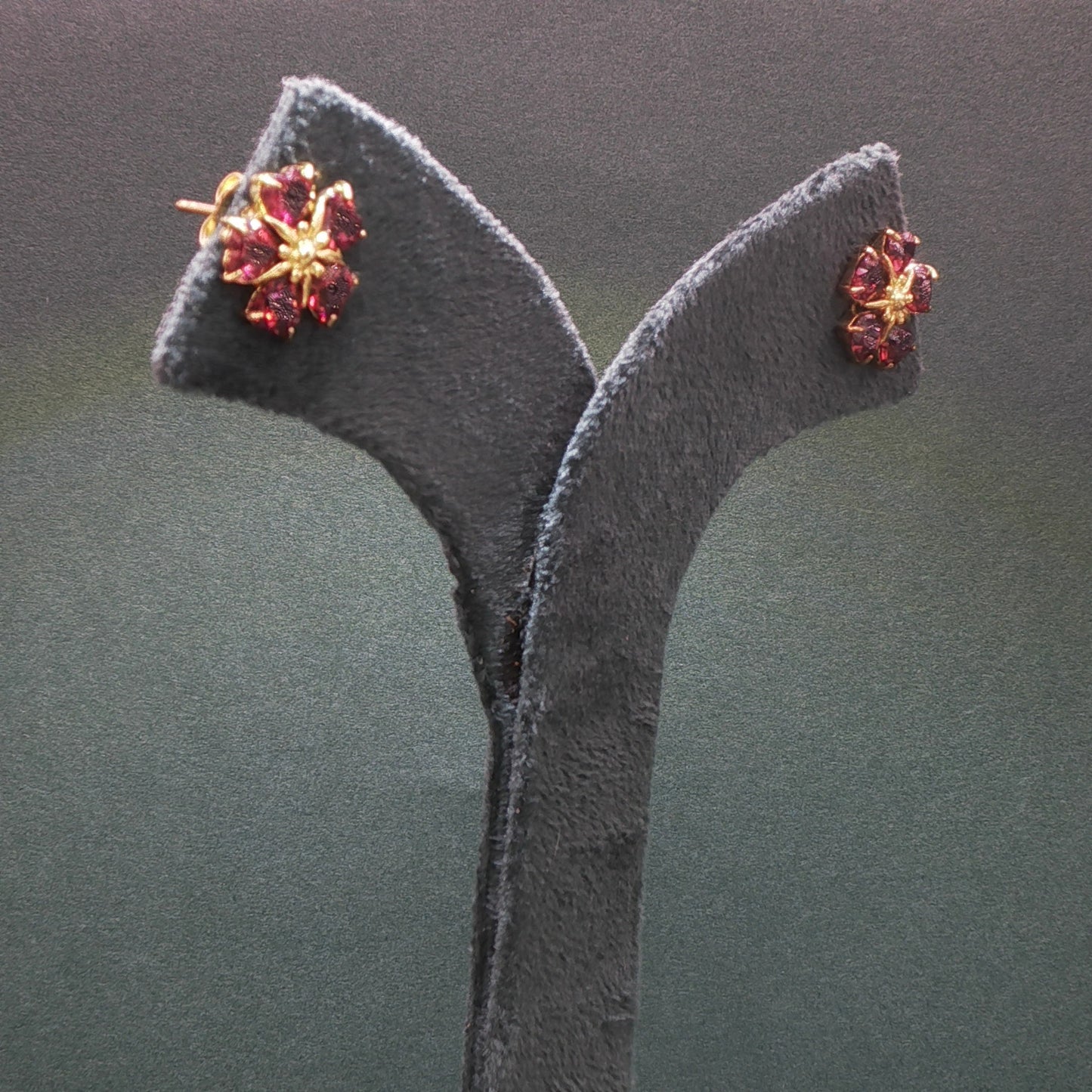 Pair of earrings on a gray stand against a dark background