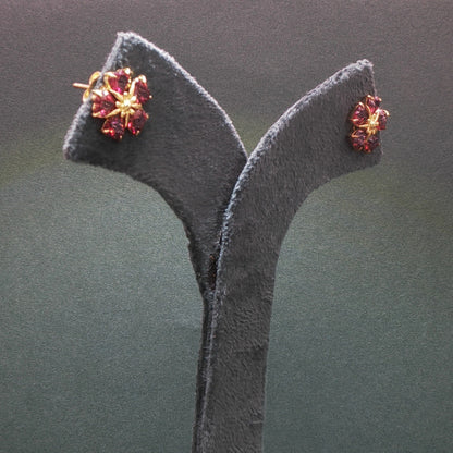 Pair of earrings on a gray stand against a dark background