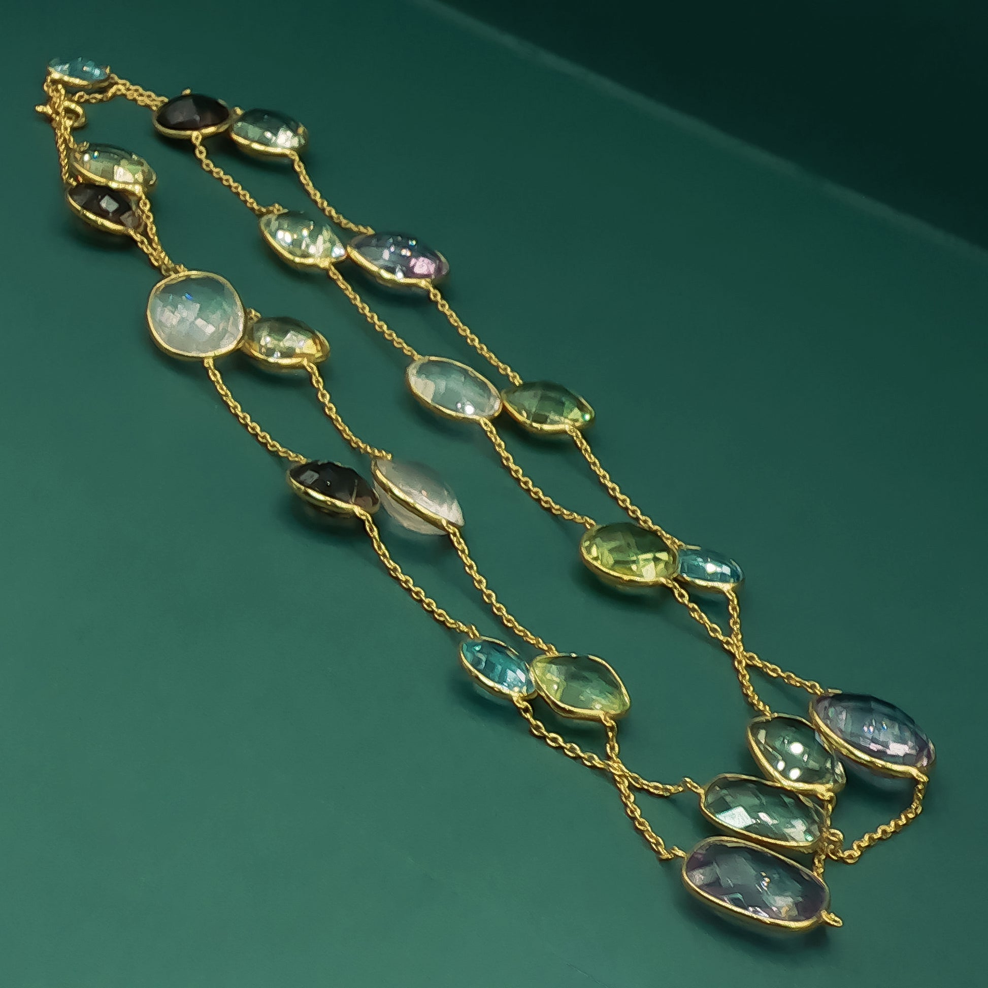 Gold necklace with green gemstones on a green background