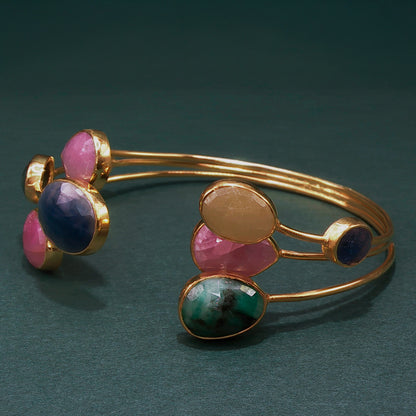 Gold bracelet with colorful gemstones on a dark green background

