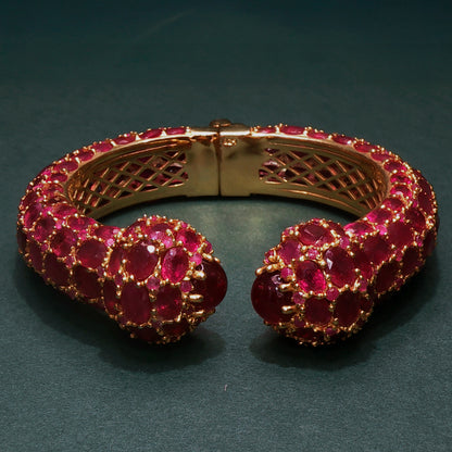 Gold bracelet with red gemstones on a dark background