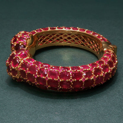 Gold bracelet with red gemstones on a dark green background