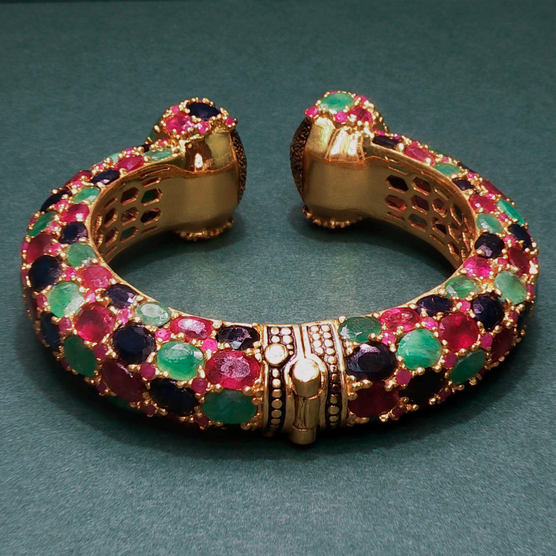 Gold bracelet with colorful gemstones on a green background