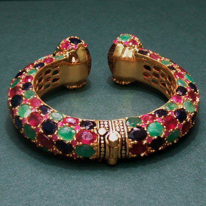Gold bracelet with colorful gemstones on a green background