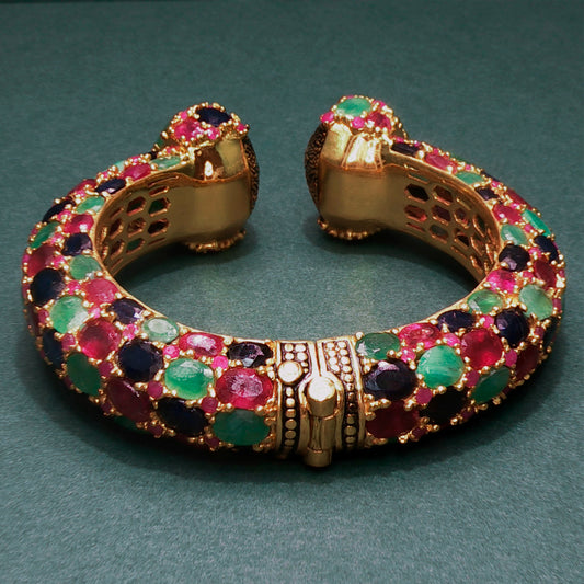 Gold bracelet with colorful gemstones on a green background