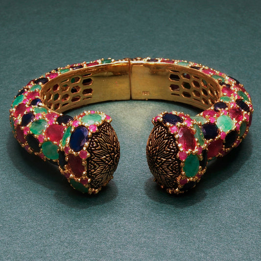 Gold bracelet with colorful gemstones on a green background