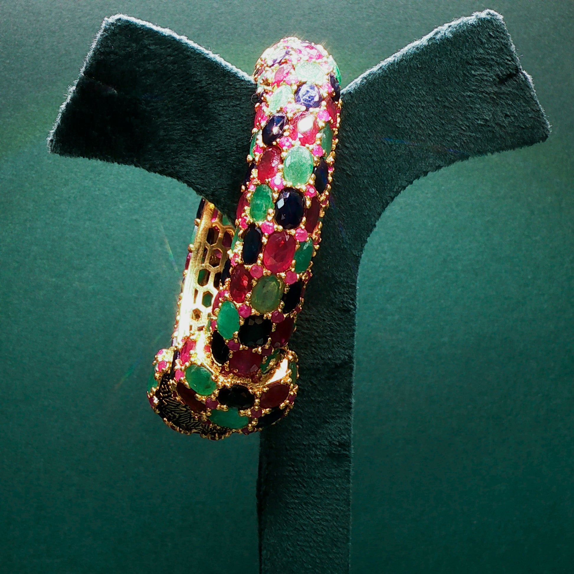 Multicolored gemstone bracelet on a green stand against a green background