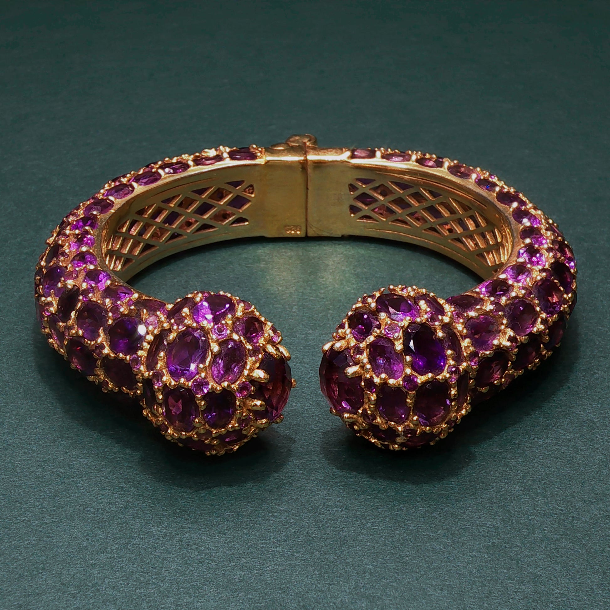 Gold bracelet with purple gemstones on a green background
