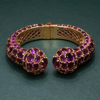 Gold bracelet with purple gemstones on a green background