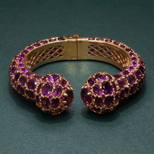 Gold bracelet with purple gemstones on a green background
