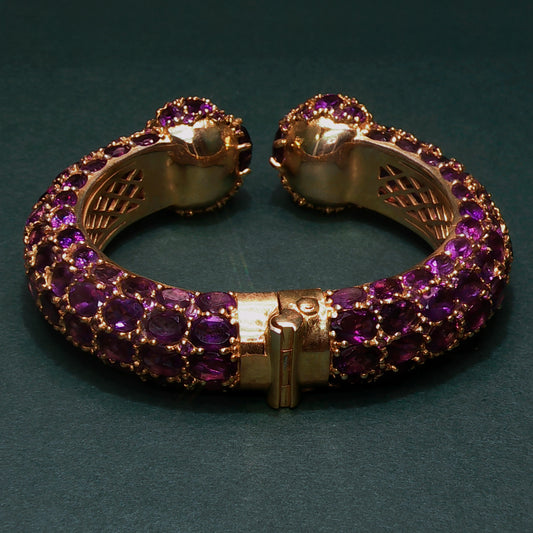Gold bracelet with purple gemstones on a dark green background