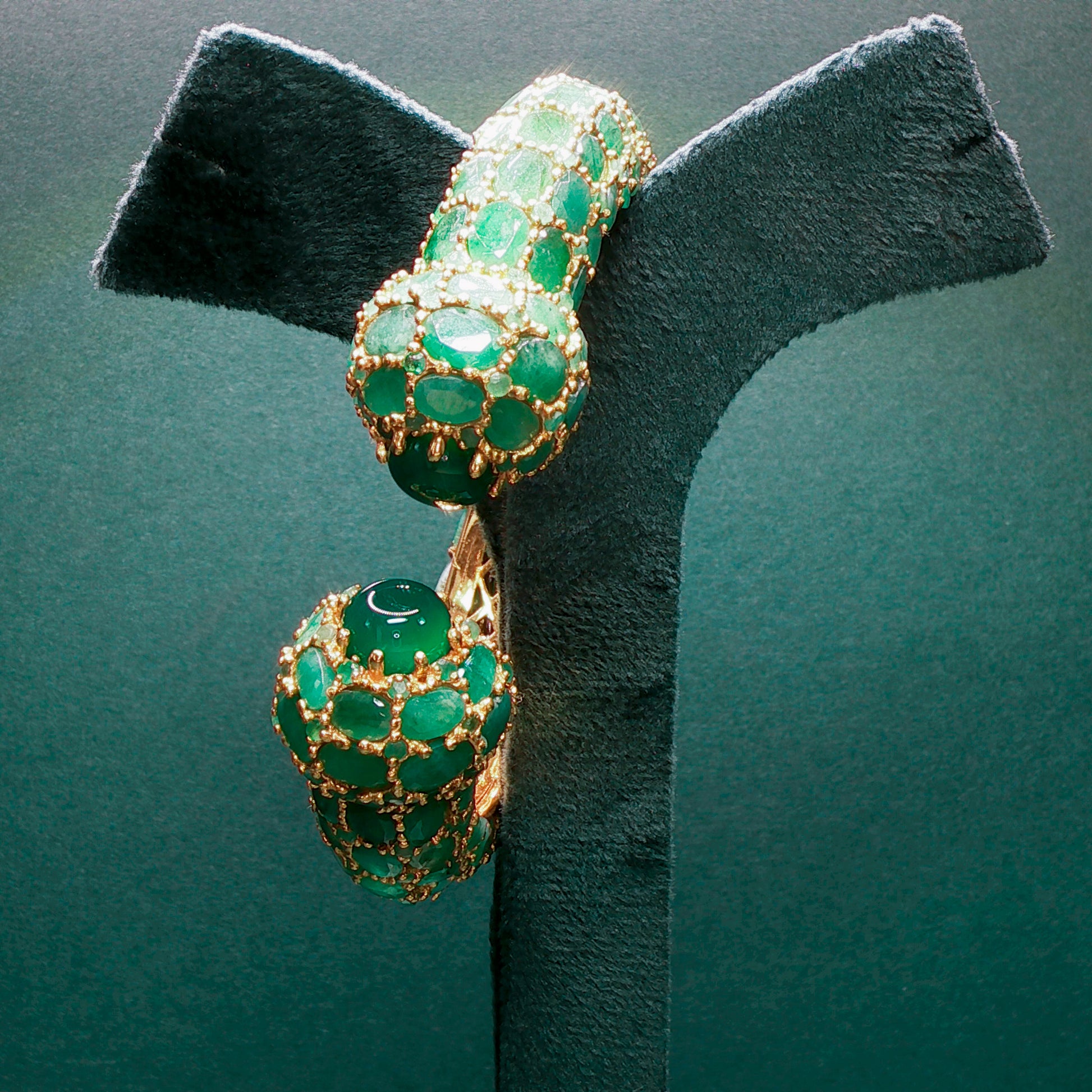 silver bracelet with green gemstones on a dark green background

