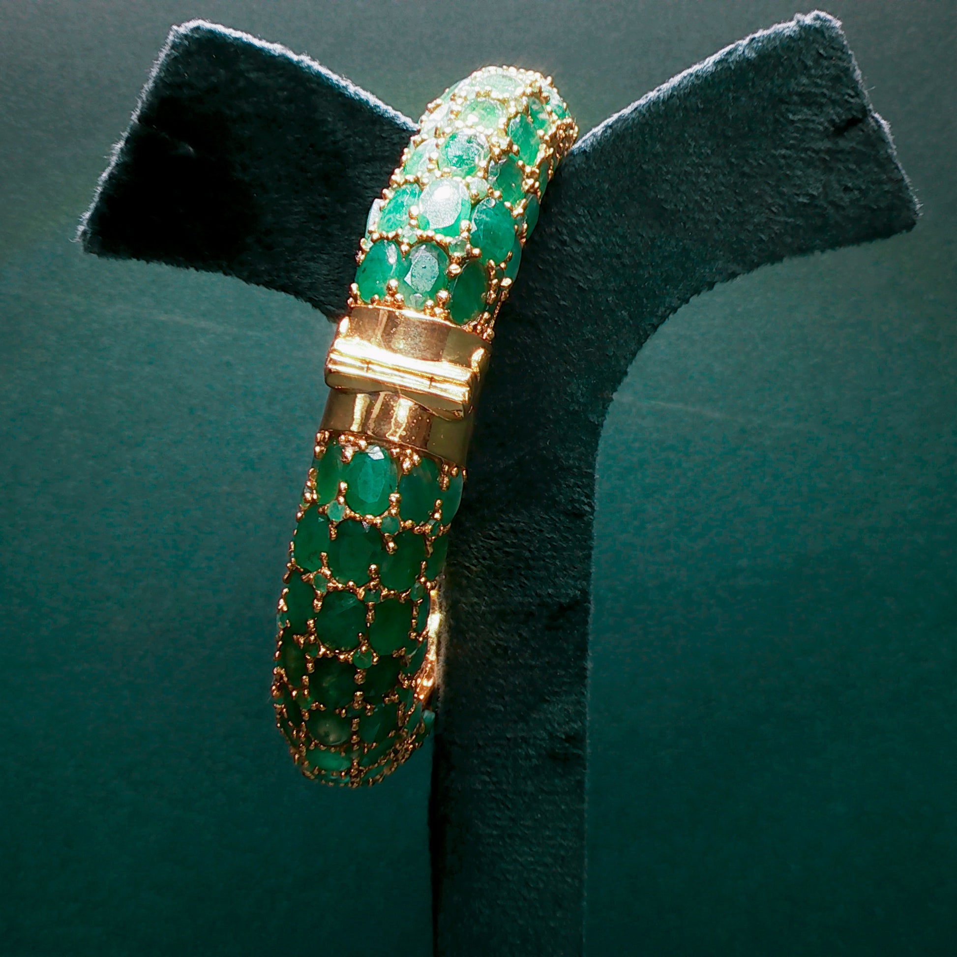 silver bracelet with green gemstones on a dark green background

