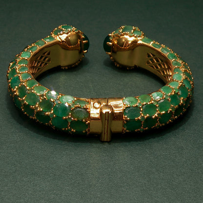 silver bracelet with green gemstones on a dark green background

