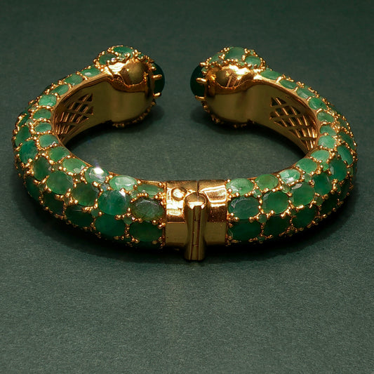 silver bracelet with green gemstones on a dark green background

