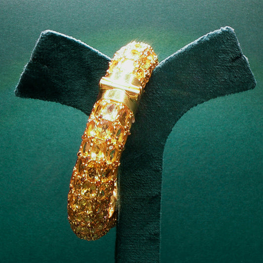 Gold bracelet on a green stand with a green background