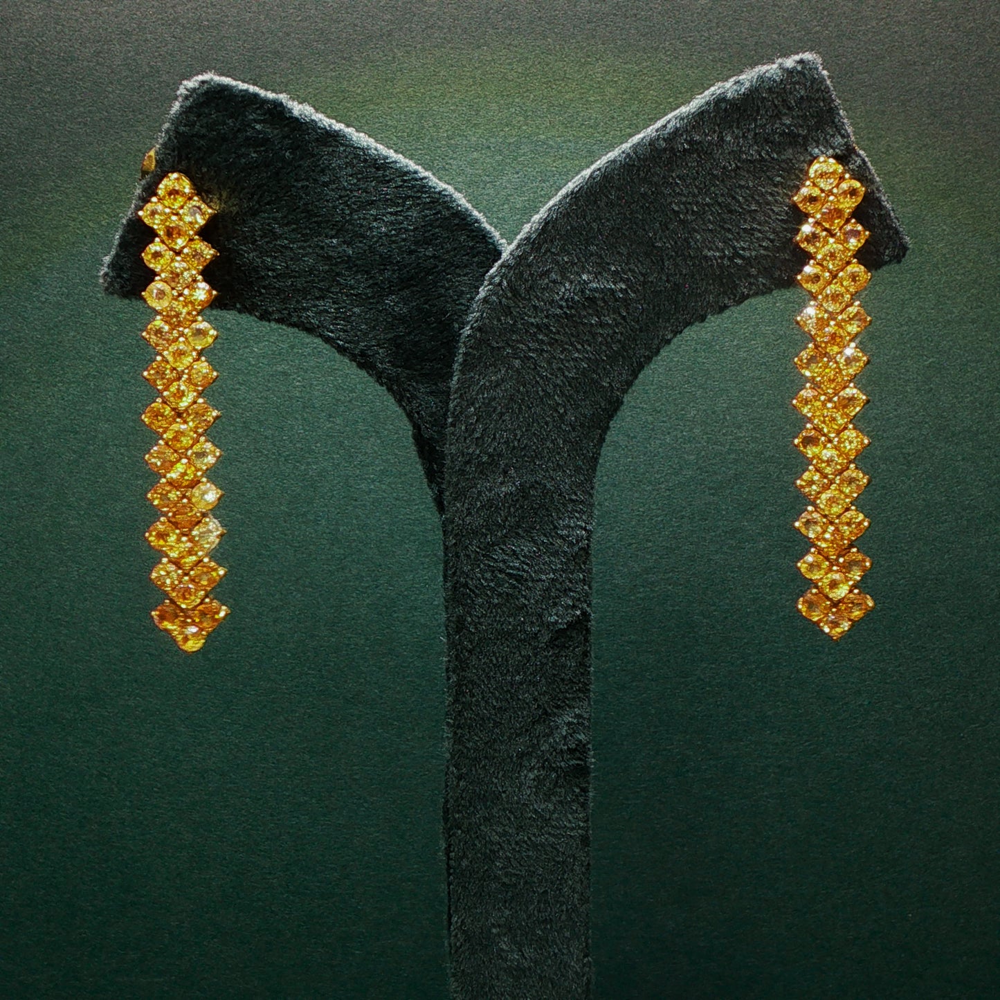 Pair of gold earrings on a green velvet stand