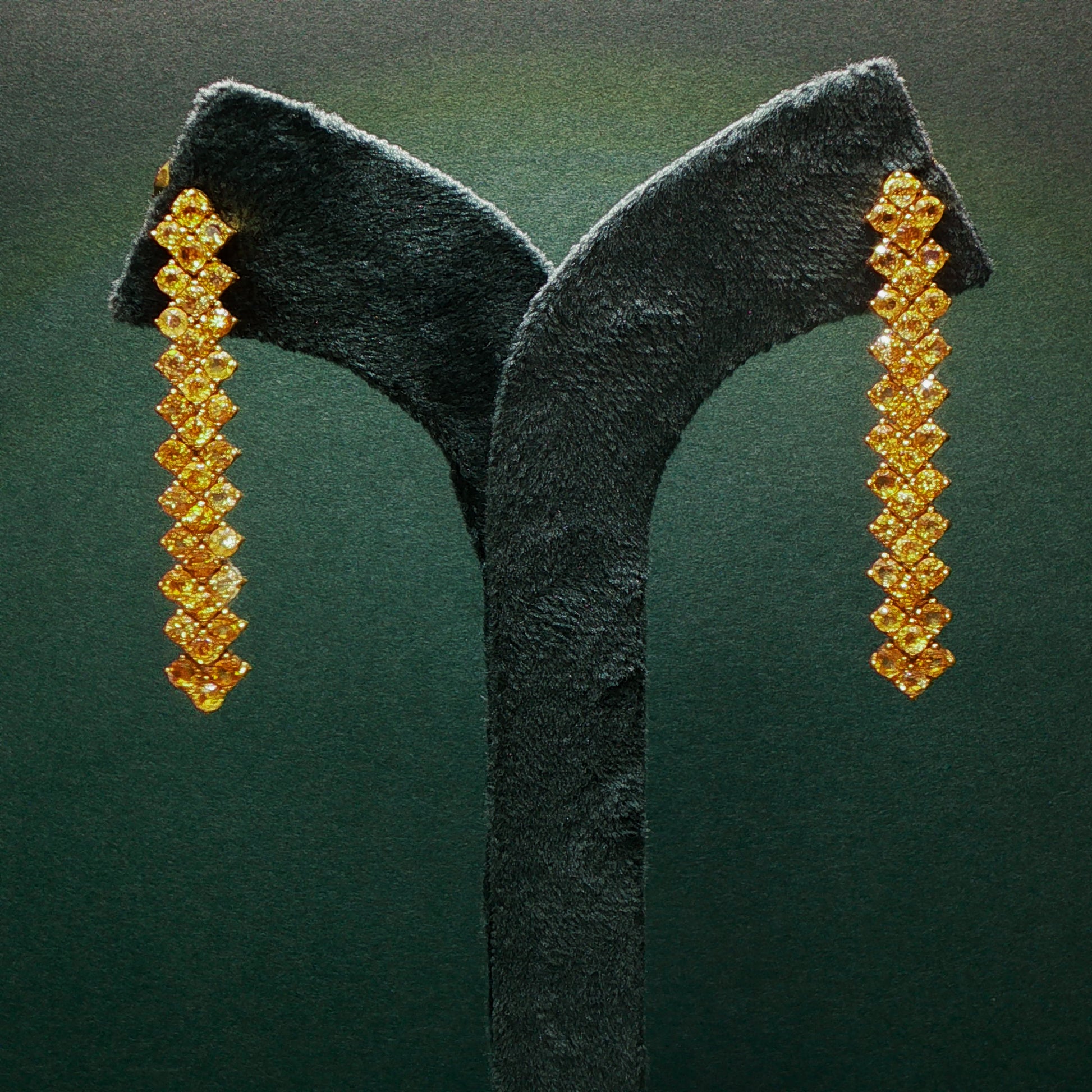 Pair of gold earrings on a green velvet stand