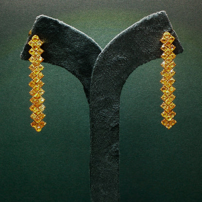 Pair of gold earrings on a green velvet stand