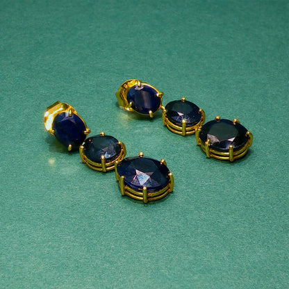 Set of gold and blue gemstone earrings on a green background