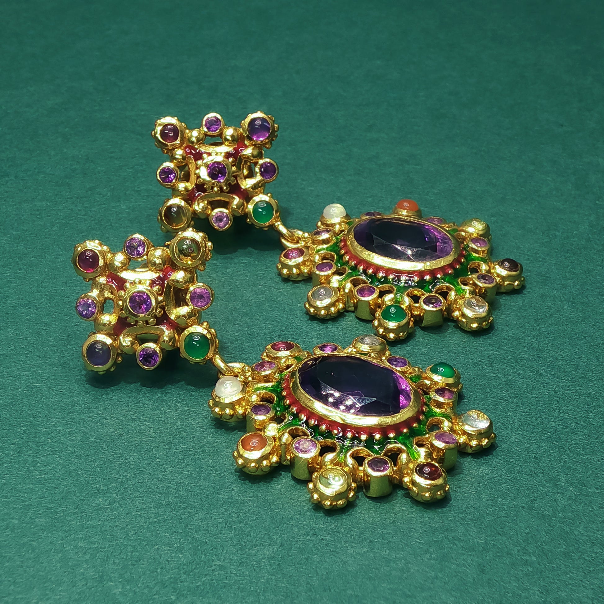 Gold earrings with gemstones on a green background