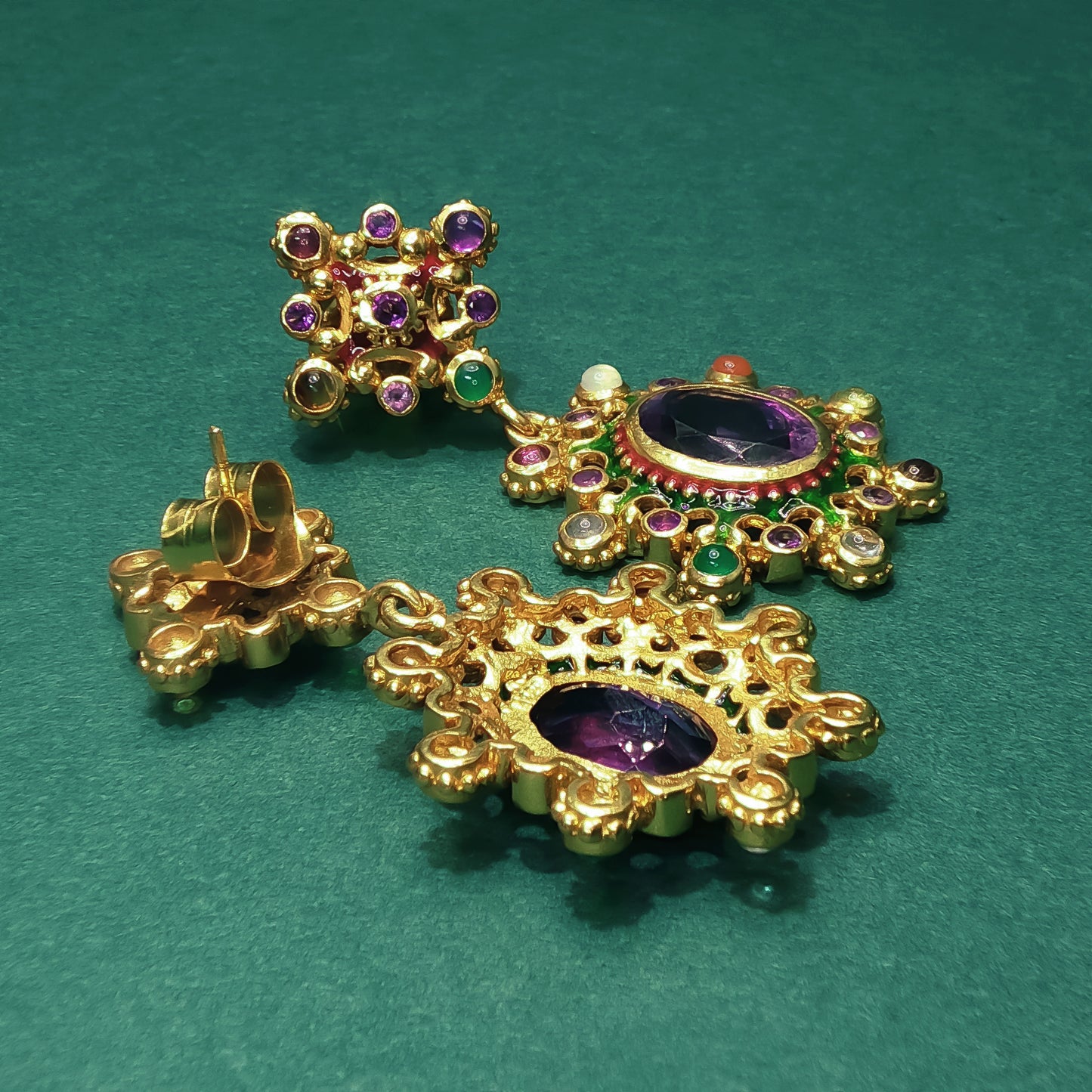 Gold earrings with gemstones on a green background